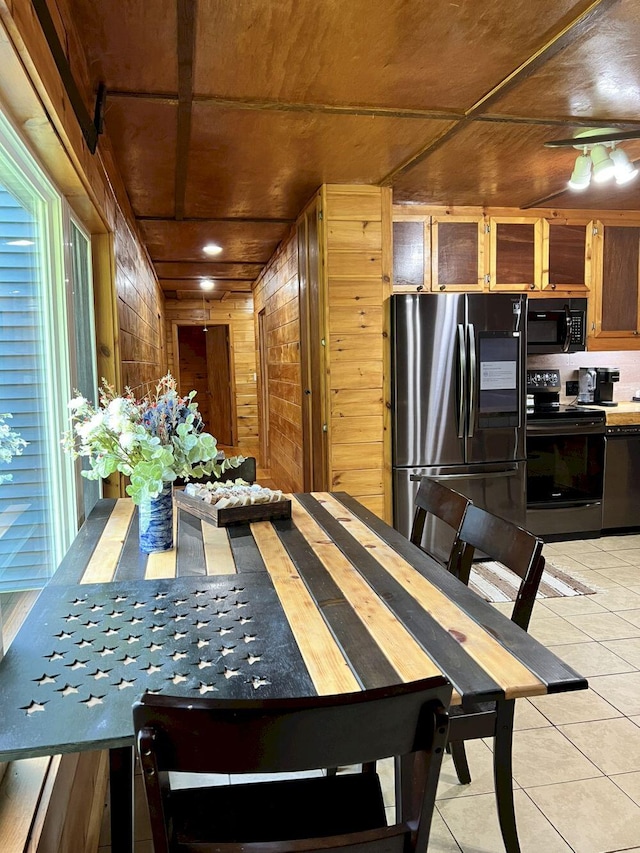 dining room featuring wooden ceiling, light tile patterned floors, and wood walls