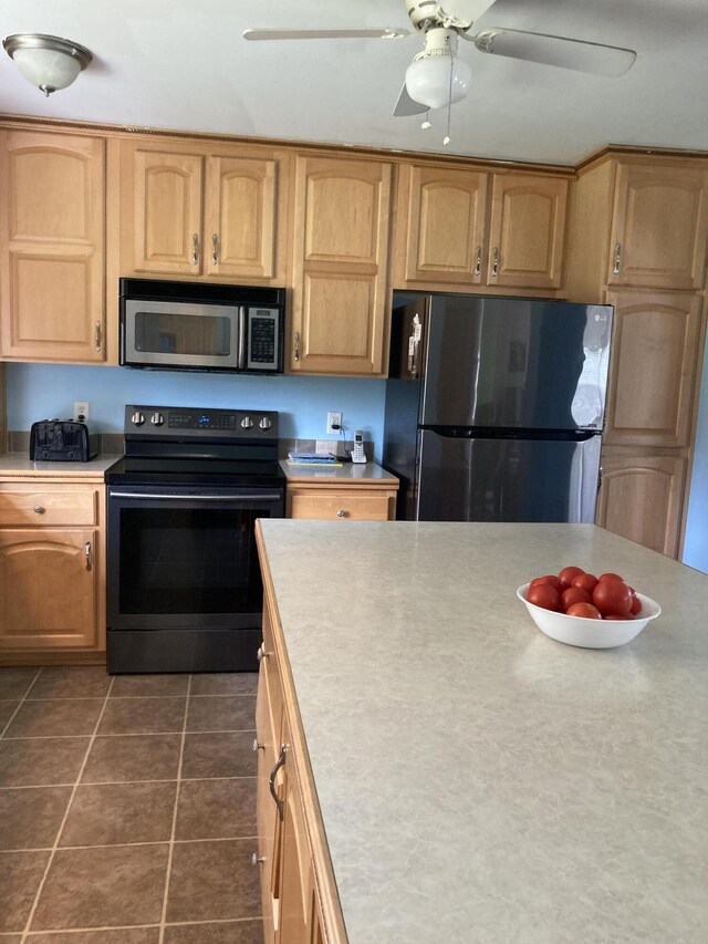 kitchen featuring ceiling fan, stainless steel appliances, and dark tile patterned floors