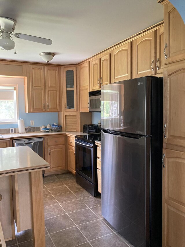 kitchen with ceiling fan, appliances with stainless steel finishes, light brown cabinetry, and dark tile patterned floors