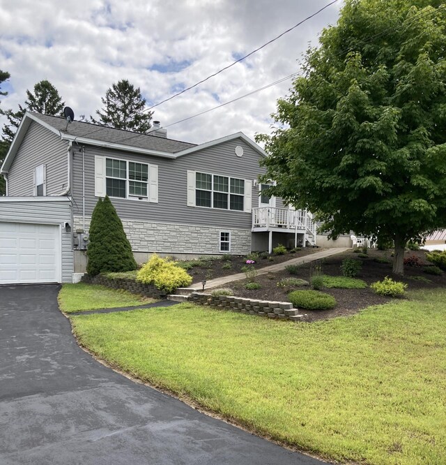 view of front of house featuring a garage, a wooden deck, and a front lawn