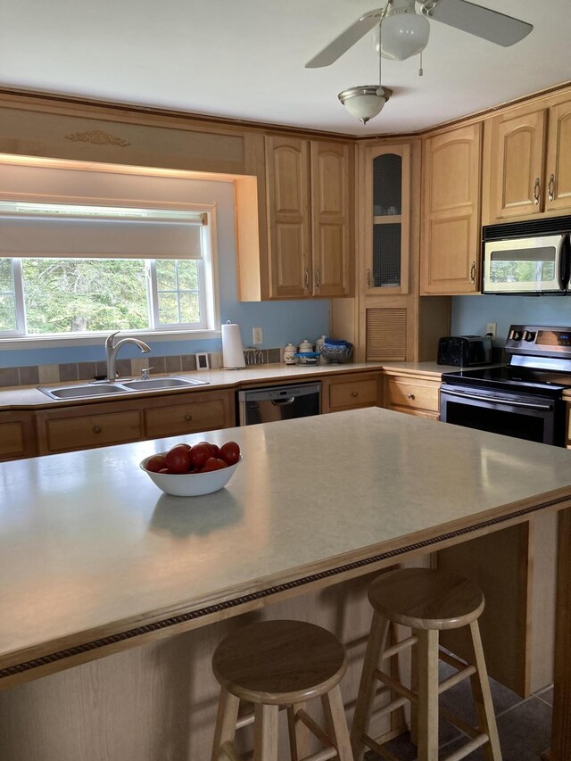 kitchen with sink, a breakfast bar, ceiling fan, and appliances with stainless steel finishes