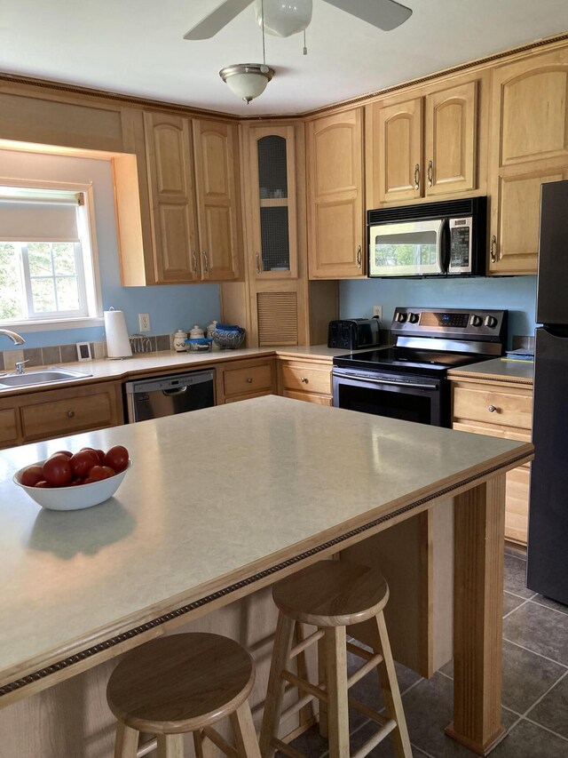 kitchen with ceiling fan, a kitchen breakfast bar, sink, and black appliances