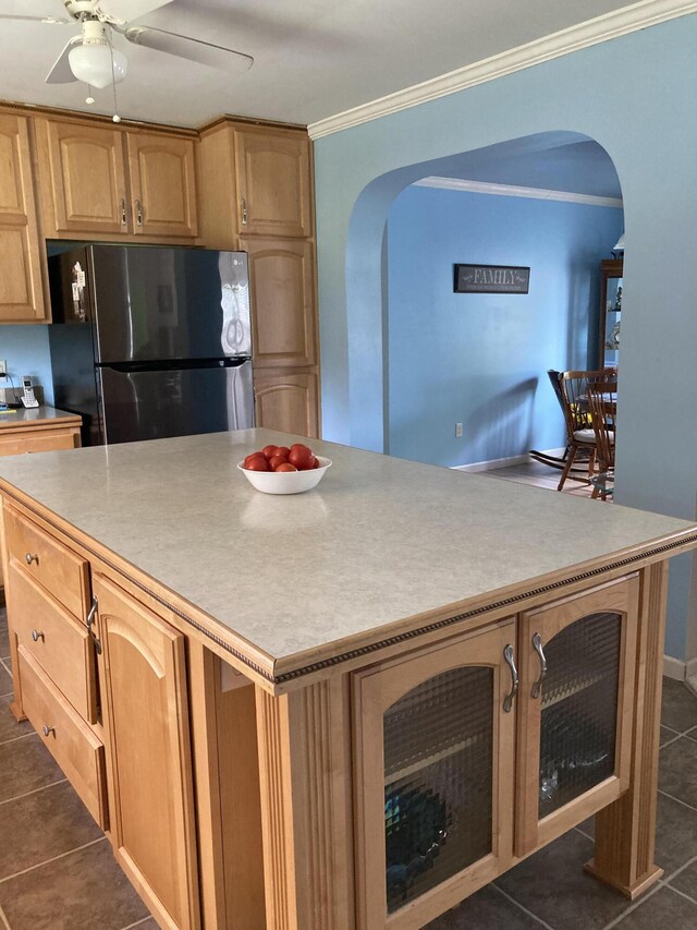 kitchen featuring stainless steel refrigerator, ceiling fan, a center island, ornamental molding, and dark tile patterned flooring