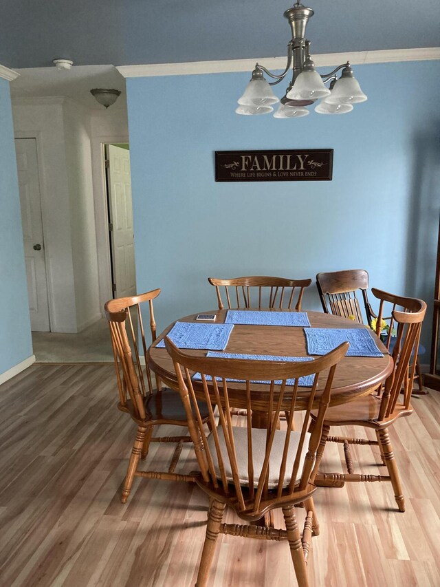 dining room with ornamental molding, a chandelier, and hardwood / wood-style floors