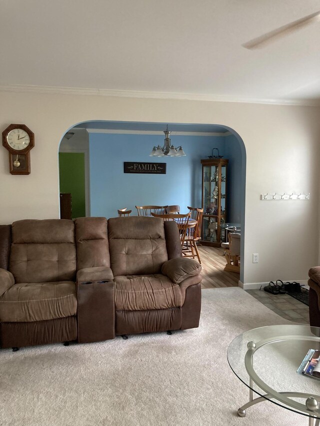 carpeted living room featuring crown molding and a notable chandelier