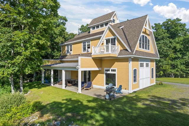 rear view of house with a lawn, a balcony, and a patio