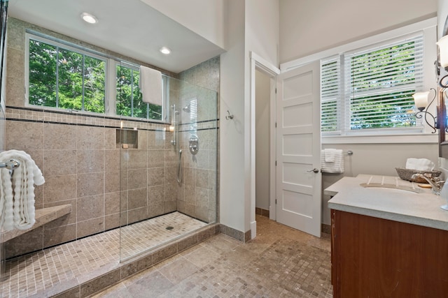 bathroom with plenty of natural light, a tile shower, and vanity