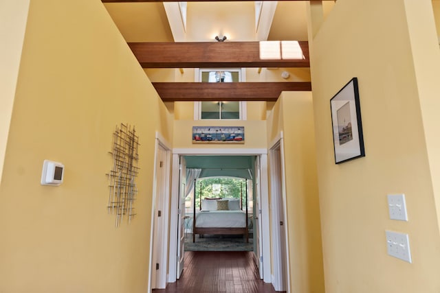 hall with a towering ceiling, dark hardwood / wood-style flooring, and beamed ceiling