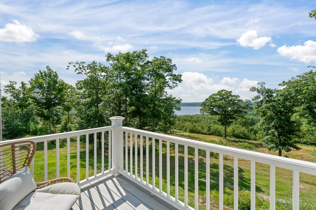 wooden deck with a water view and a lawn