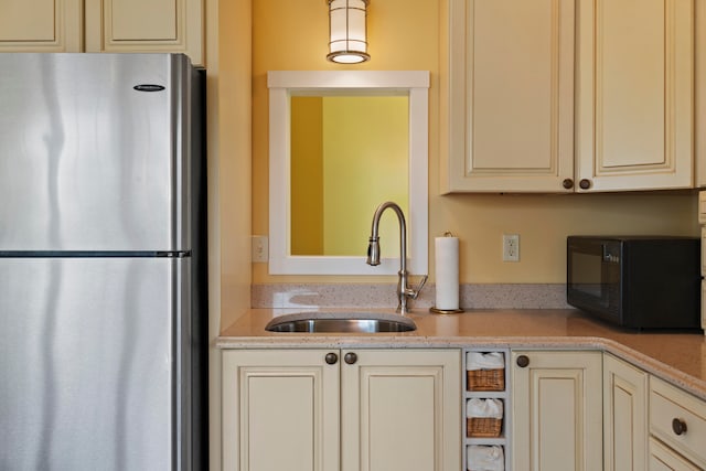 kitchen featuring cream cabinetry, stainless steel fridge, and sink