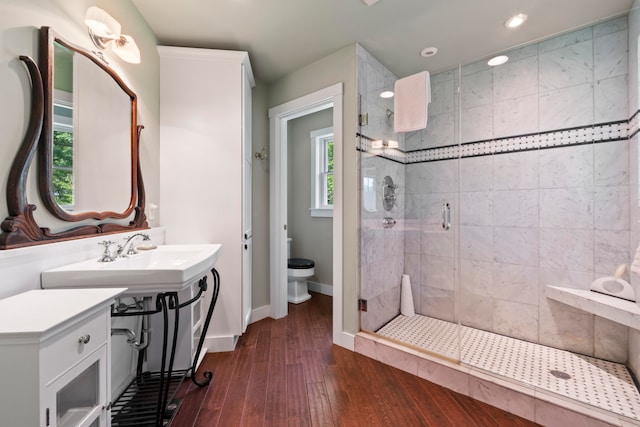 bathroom with wood-type flooring, toilet, plenty of natural light, and a shower with shower door