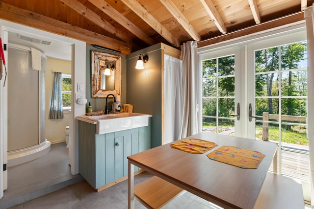 dining space with light tile patterned floors, vaulted ceiling with beams, and a healthy amount of sunlight