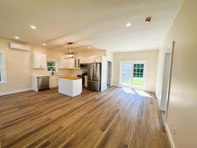 kitchen with white cabinets, a center island, stainless steel appliances, and wood-type flooring