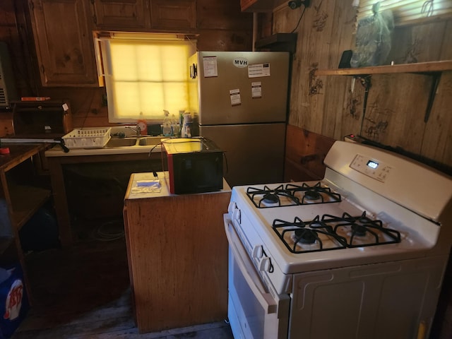 kitchen featuring stainless steel fridge, gas range gas stove, and wooden walls