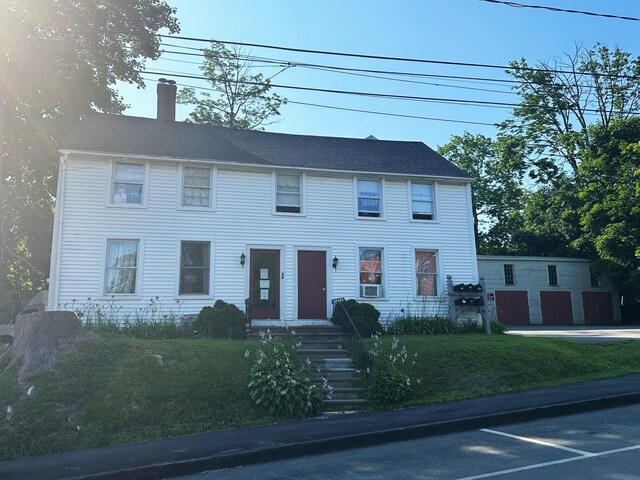 colonial home featuring a front lawn and a chimney