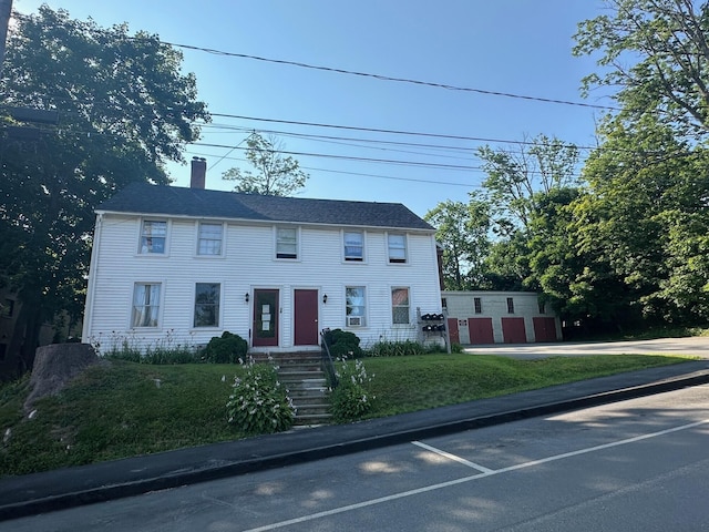 colonial home featuring a chimney and a front lawn