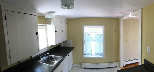 kitchen featuring a baseboard heating unit, sink, and white cabinetry