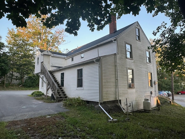 view of side of home with stairway and a chimney