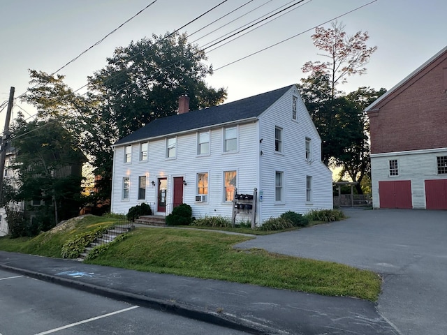 colonial inspired home featuring a chimney and a front yard