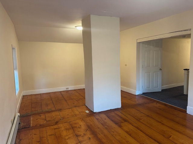 unfurnished room with baseboard heating, wood-type flooring, and baseboards