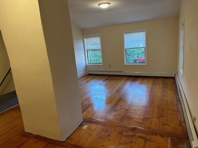 unfurnished room with a baseboard heating unit, hardwood / wood-style floors, and baseboard heating