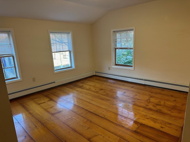 empty room featuring lofted ceiling, a wealth of natural light, a baseboard heating unit, and hardwood / wood-style floors