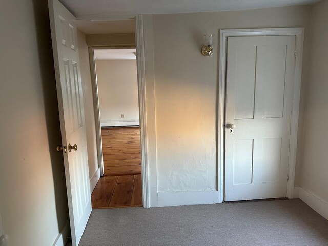 unfurnished bedroom with a baseboard heating unit and wood-type flooring