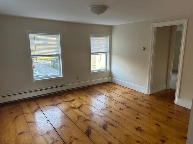 spare room with hardwood / wood-style flooring, a baseboard radiator, and a wealth of natural light