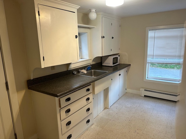 kitchen with baseboard heating, sink, and white cabinetry