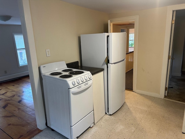 kitchen with dark countertops, white appliances, baseboards, and light floors