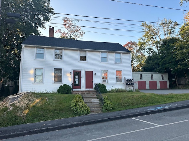 colonial-style house featuring a chimney and a front yard