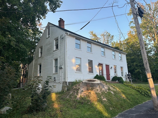 colonial inspired home with a chimney and a front yard