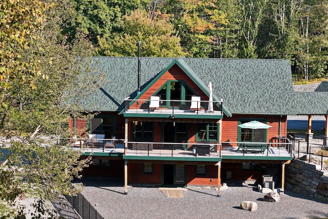 rear view of house featuring a shingled roof, a wooden deck, and a balcony