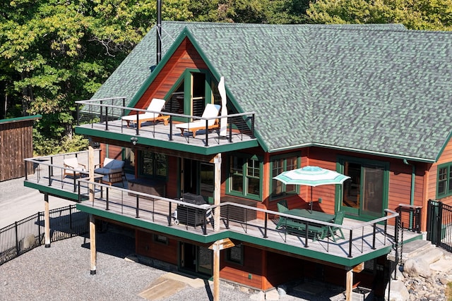 back of property with an outdoor living space, a wooden deck, and a shingled roof