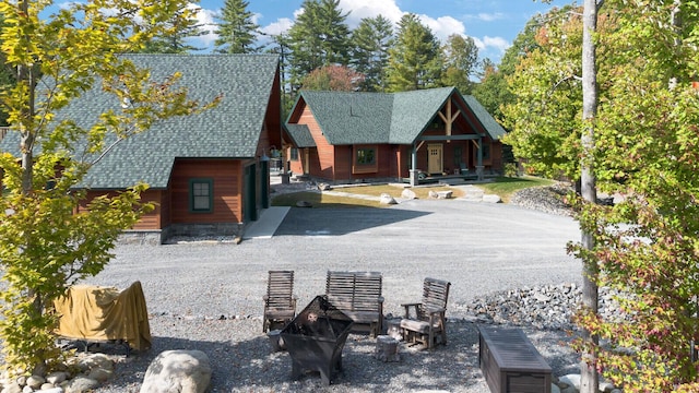 view of front of property with a porch, a fire pit, and roof with shingles