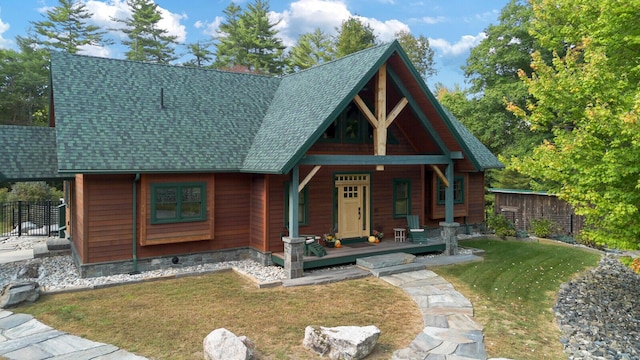 view of front of property featuring a shingled roof, fence, a porch, and a front yard