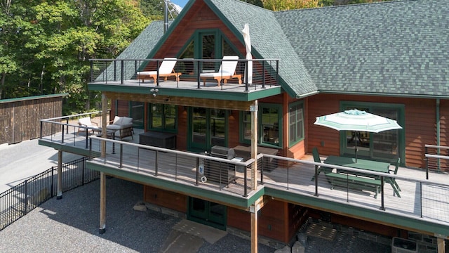 back of property featuring a balcony, a wooden deck, a shingled roof, french doors, and an outdoor living space