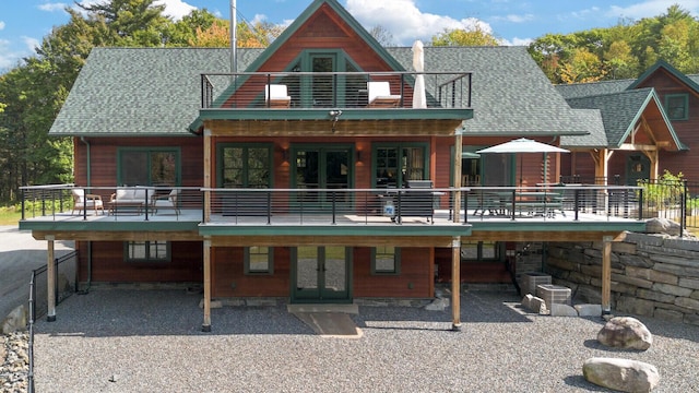 back of house with roof with shingles, central AC unit, french doors, and a balcony