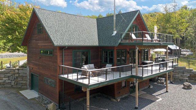 back of property with a wooden deck, a shingled roof, and a balcony