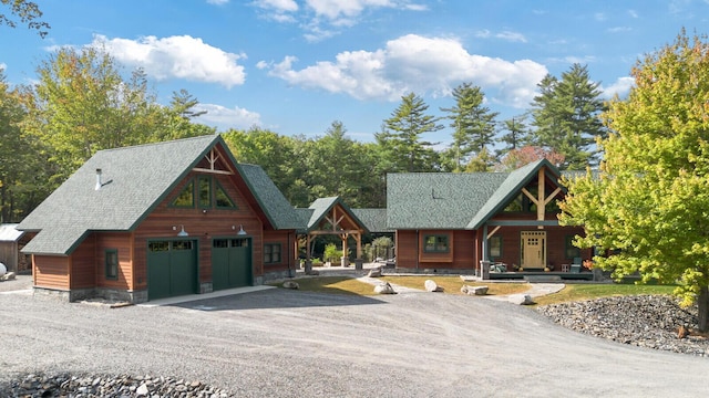 rustic home featuring driveway, roof with shingles, a porch, and a garage
