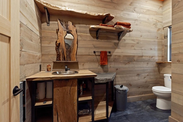 bathroom with toilet, wooden walls, and vanity