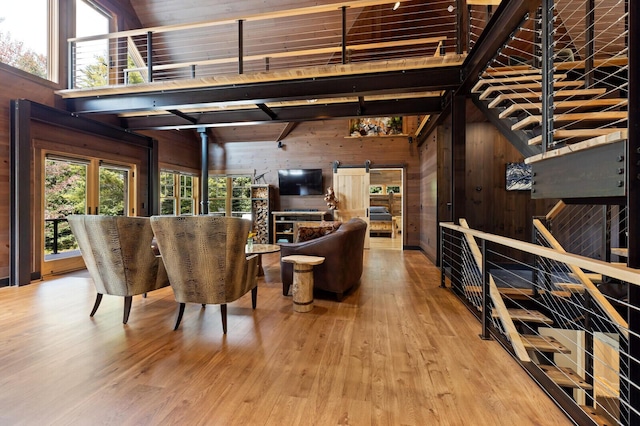 living room with a barn door, wood walls, wood finished floors, and a healthy amount of sunlight