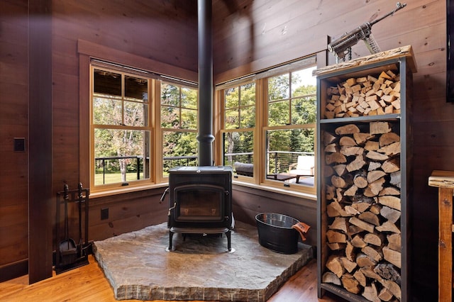 sitting room with wood walls, a healthy amount of sunlight, light wood-style flooring, and a wood stove
