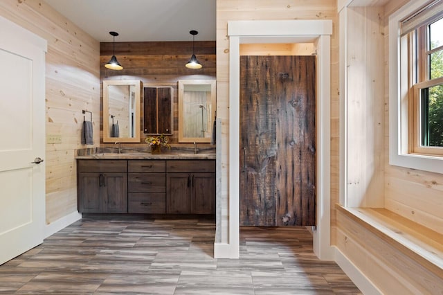 full bath with a sink, double vanity, and wood walls