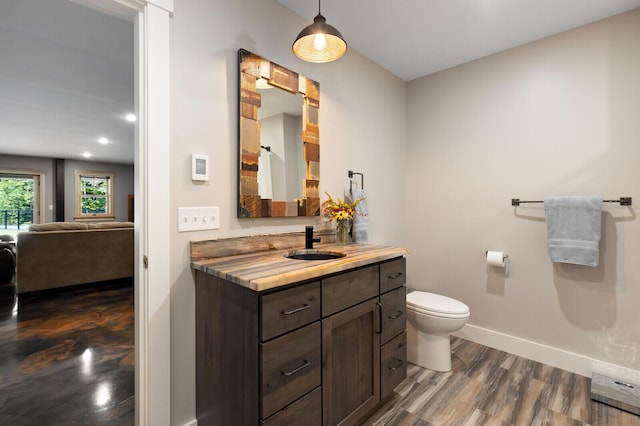 ensuite bathroom with wood finished floors, ensuite bath, toilet, vanity, and baseboards