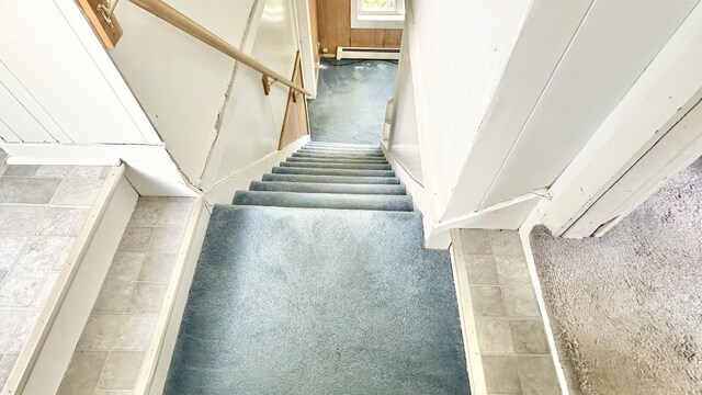 stairs with a baseboard heating unit and carpet