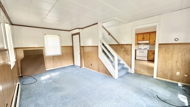 interior space with a baseboard heating unit, carpet flooring, wood walls, and crown molding