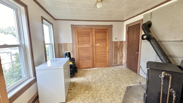 interior space with light carpet, wood walls, a wood stove, and crown molding