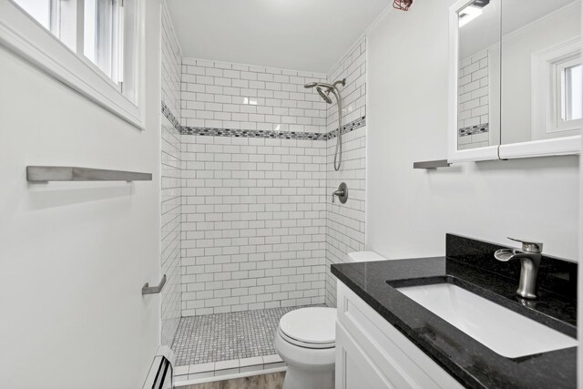 bathroom featuring vanity, toilet, wood-type flooring, and tiled shower