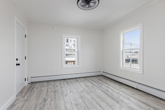 unfurnished room featuring baseboard heating, a wealth of natural light, and light hardwood / wood-style floors